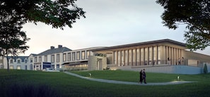 Un hôtel moderne doté d’une grande entrée, d’une façade en pierre et d’une galerie couverte.