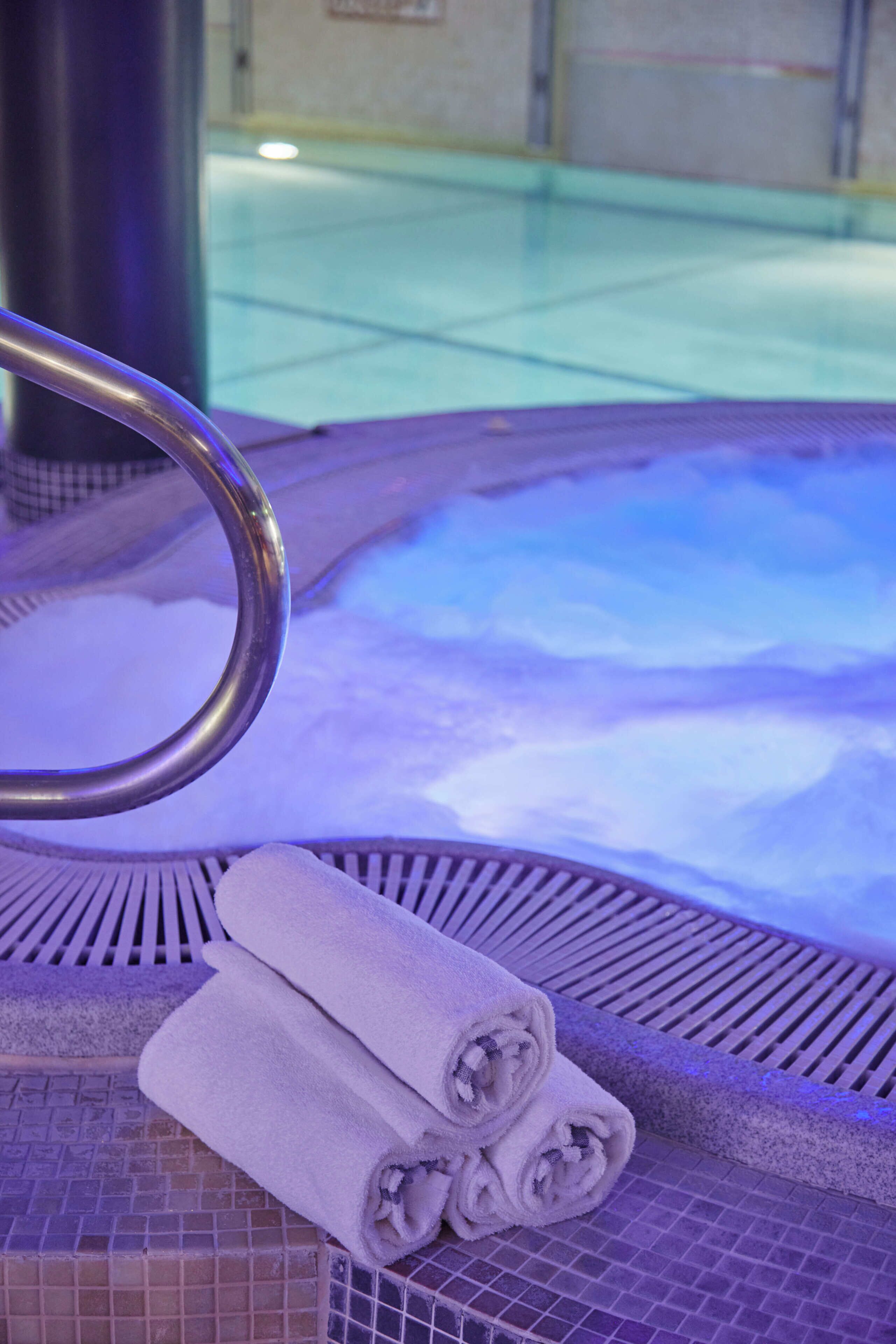Un jacuzzi con barandilla metálica y toallas enrolladas.