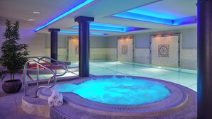 Een wellnessruimte met een bubbelbad, een trap en een potplant.