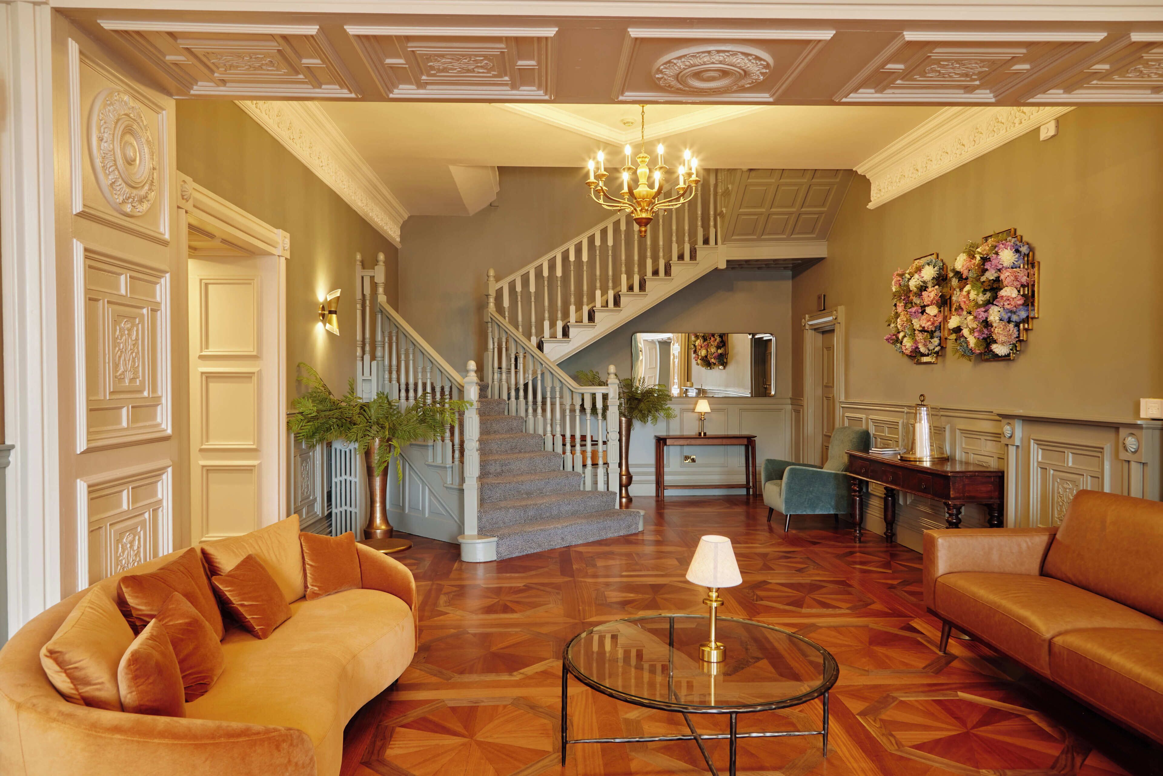 Un vaste salon agrémenté d’un magnifique escalier, d’un lustre et d’une décoration murale à motifs floraux.
