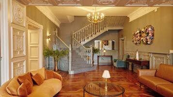 Un vaste salon agrémenté d’un magnifique escalier, d’un lustre et d’une décoration murale à motifs floraux.