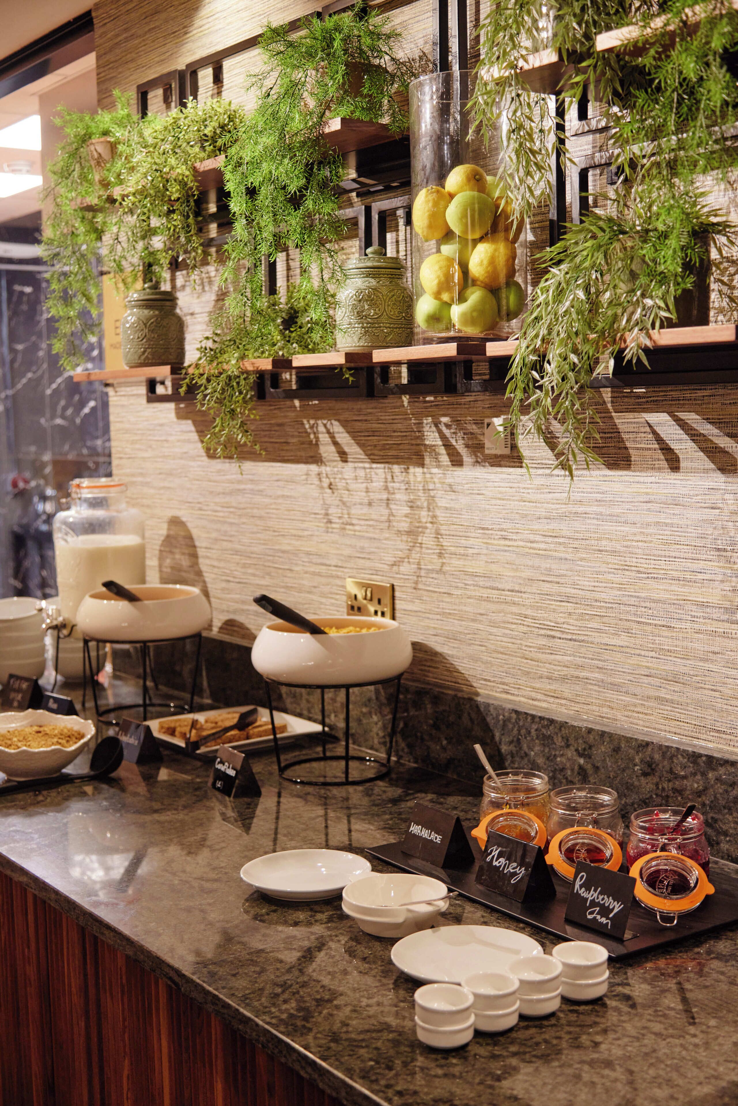 A buffet setup with various food items, including fruits, jams, and condiments, arranged on a marble counter.