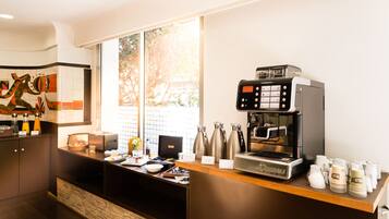 A modern coffee station with a coffee machine, cups, and a menu board.