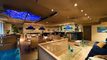 Een moderne hotel lobby met een bar, zitgedeelte en een decoratief plafond.