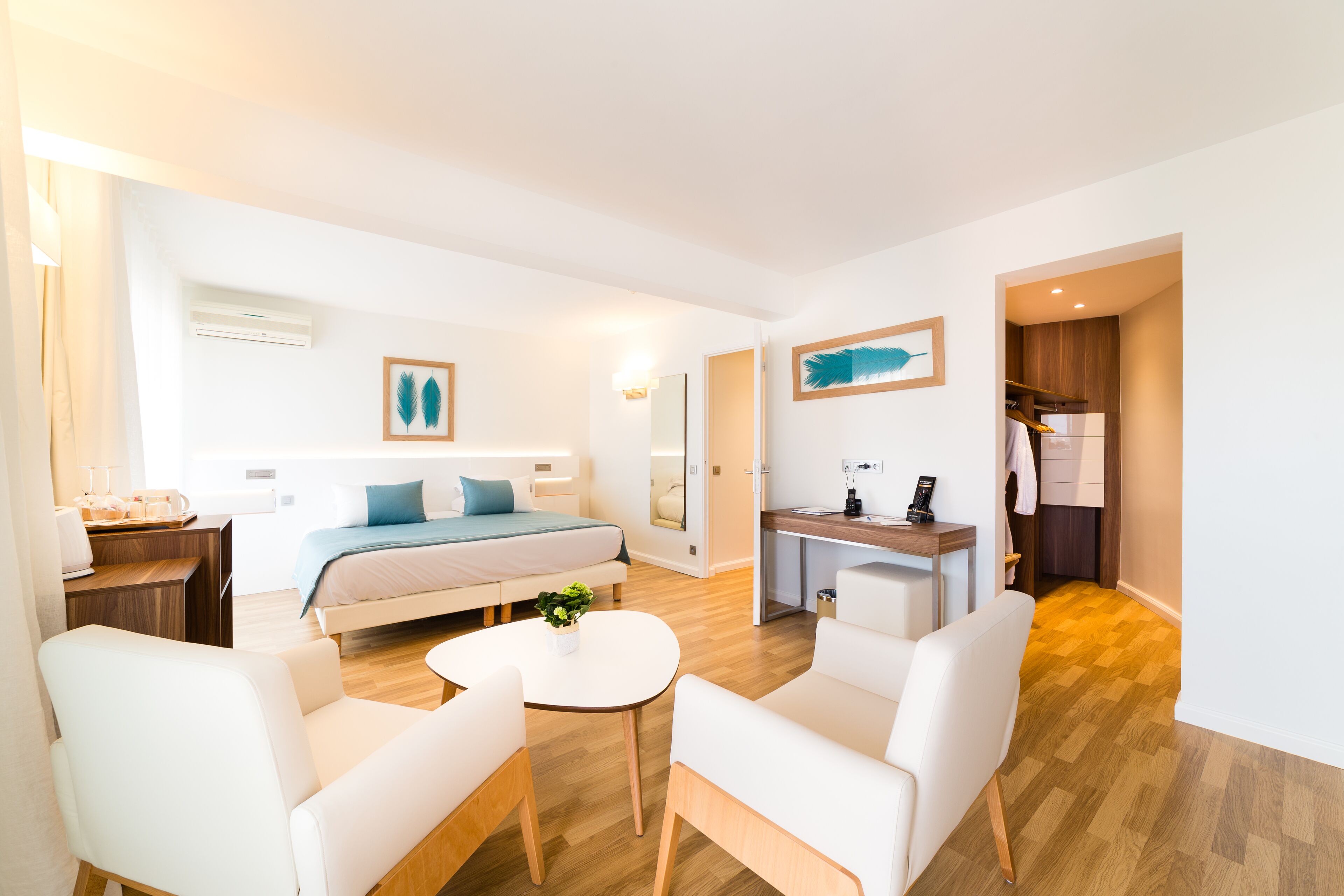 A modern hotel room with a bed, a desk, a chair, and a small table.