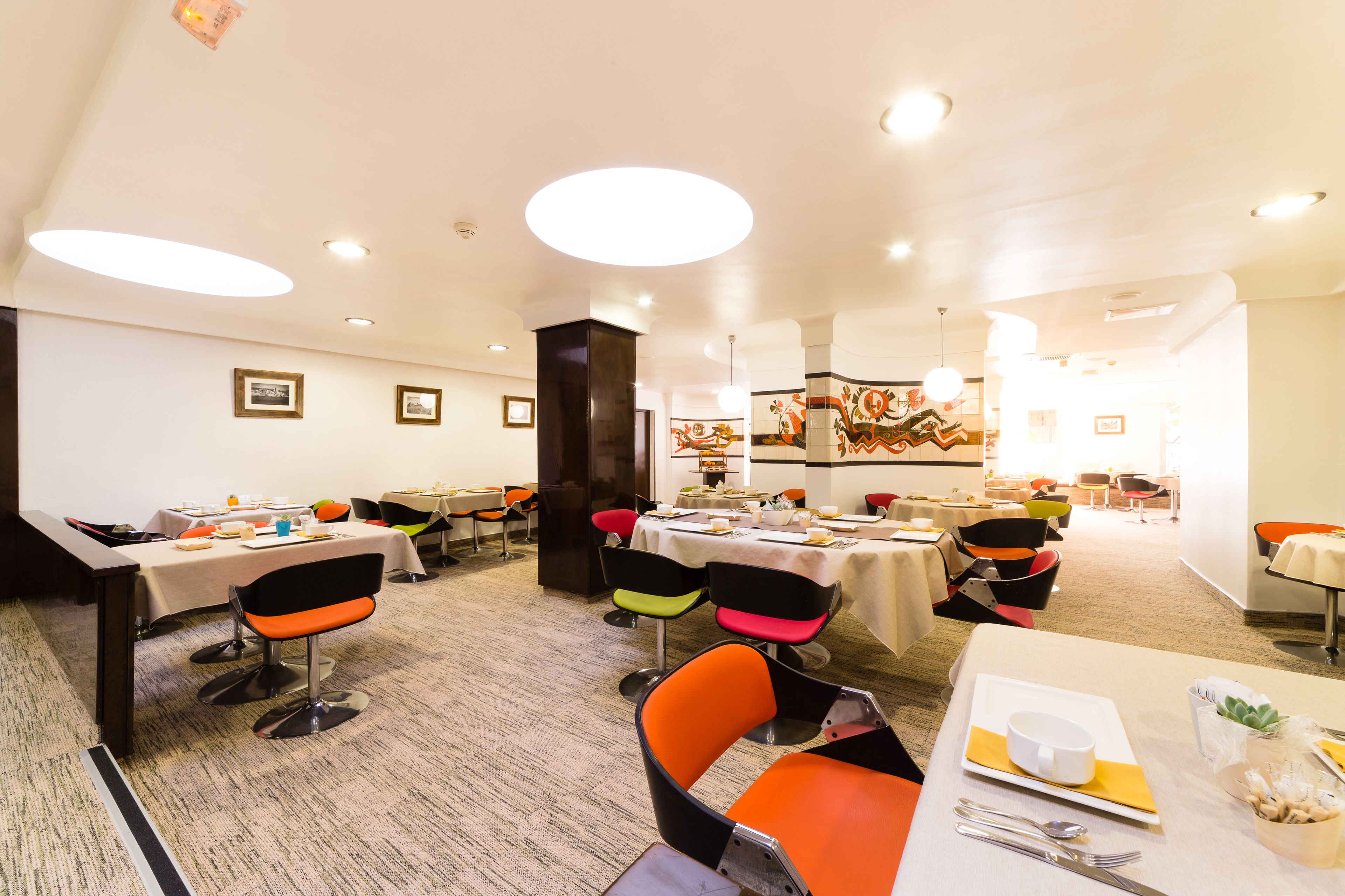 A dining area with multiple tables and chairs, featuring a modern design with a mix of colors.
