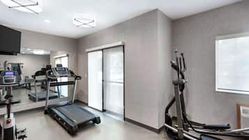 A modern gym with treadmills, elliptical machines, and weight equipment.