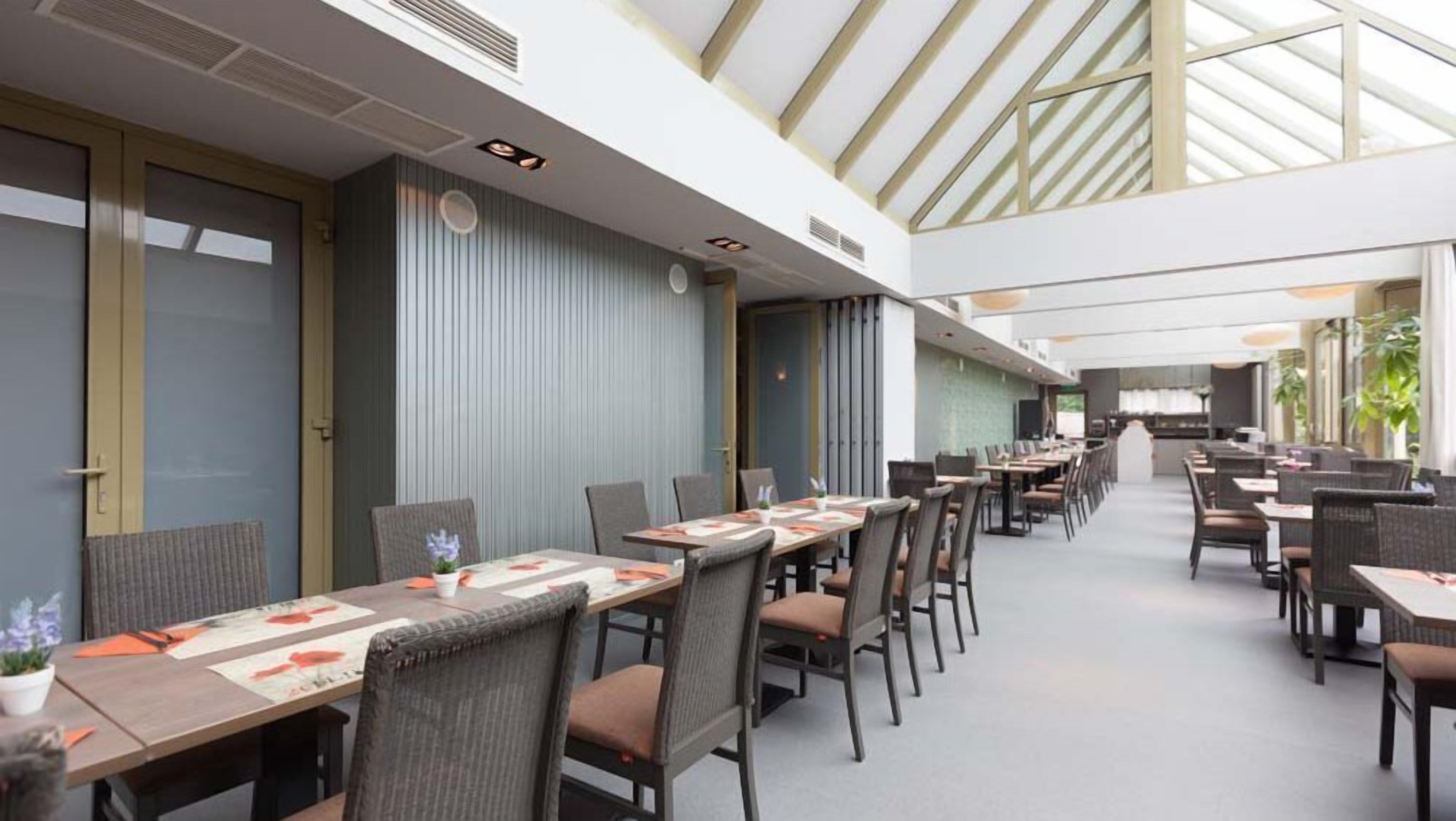 Un'ampia sala da pranzo interna, con soffitti alti e luce naturale proveniente da lucernari.