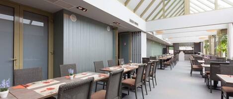 Un comedor interior amplio con techos altos e iluminación natural proveniente de tragaluces.