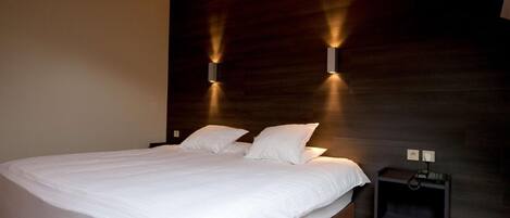 Un dormitorio moderno con una cama grande, dos mesitas de noche e iluminación en la pared.