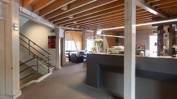 A hotel lobby with a staircase, reception desk, and a seating area.