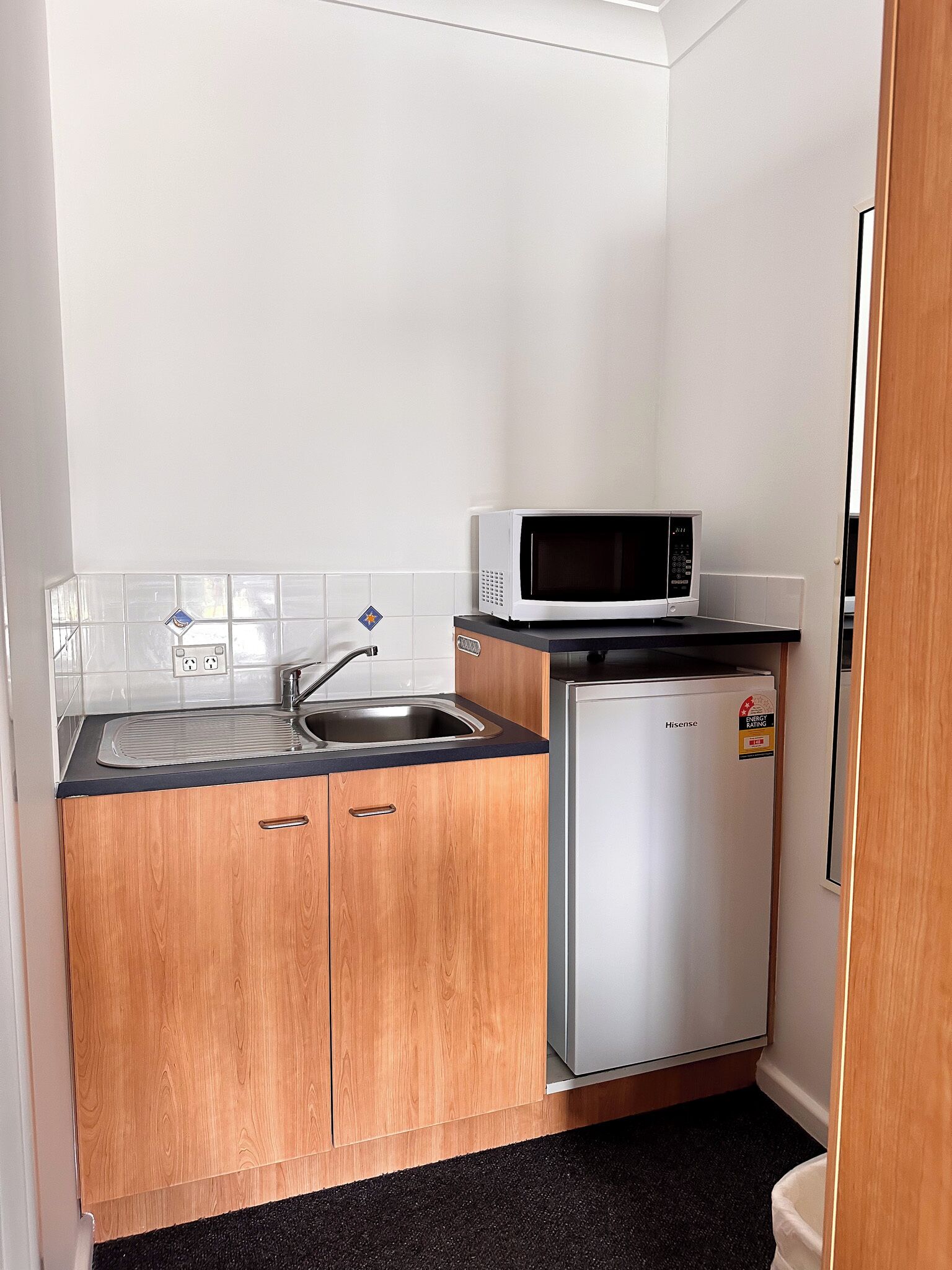 A compact kitchen with a sink, a microwave, and a small refrigerator.