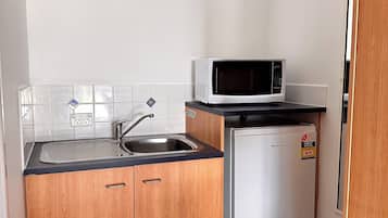 A compact kitchen with a sink, a microwave, and a small refrigerator.
