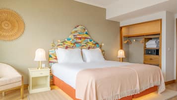 A bedroom with a bed, two bedside tables with lamps, a wardrobe, and a decorative wall hanging.