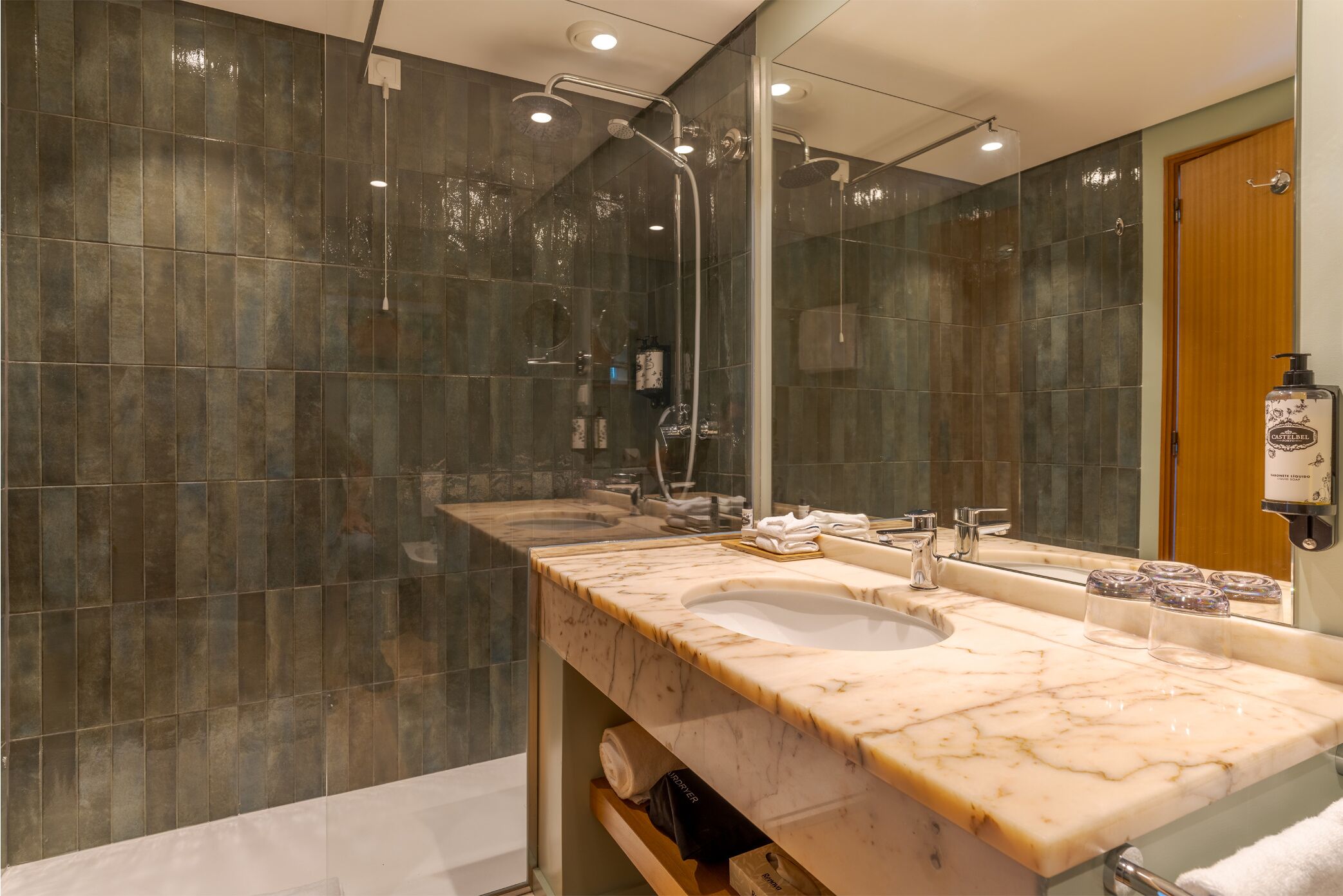 Une salle de bain moderne avec un grand miroir, deux lavabos et un espace douche.