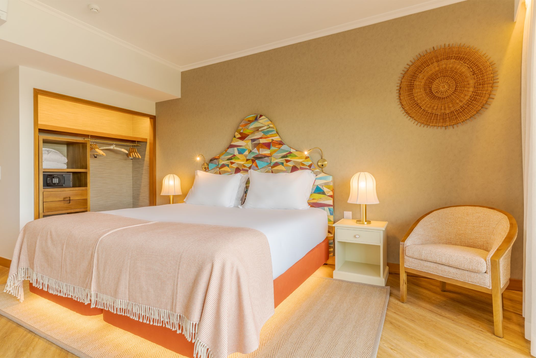 A bedroom with a bed, bedside tables, a chair, a wardrobe, and a decorative wall piece.