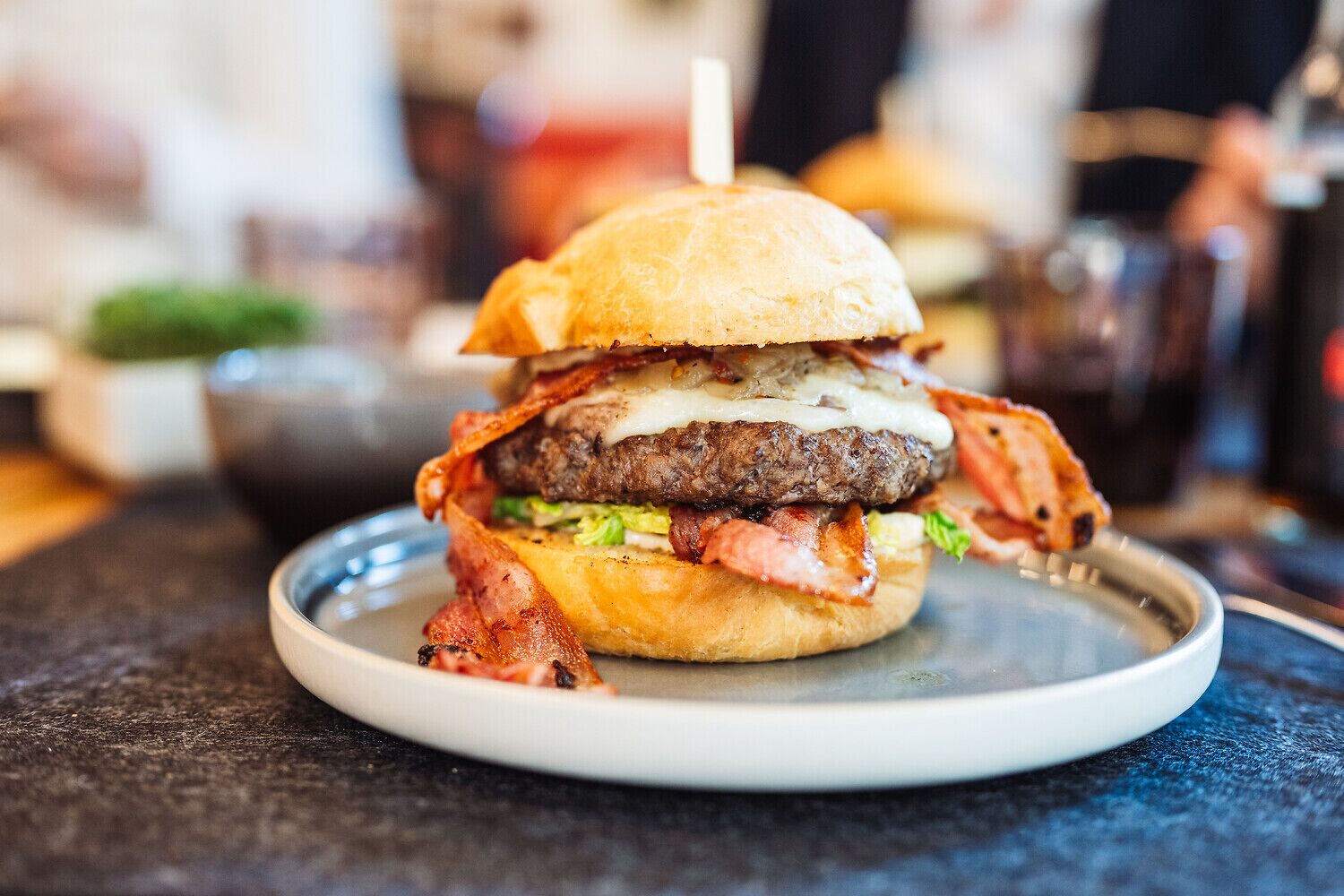 Hamburguesa con tocino, queso y lechuga sobre un plato.