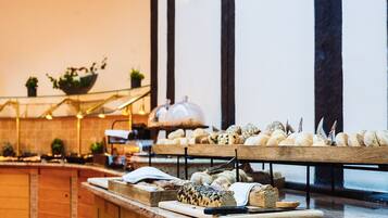 A buffet setup with various breads and pastries on wooden serving boards.