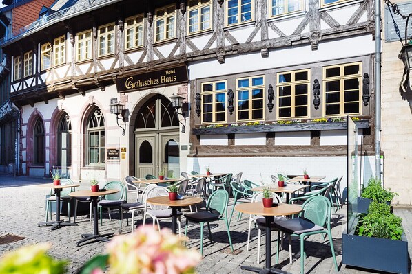 A traditional half-timbered building with a sign reading "Gothisches Haus" and outdoor seating with chairs and tables. - A-ROSA Gothisches Haus Wernigerode (Wernigerode)