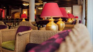A row of wicker sofas with red lamps and cushions in a well-lit room.