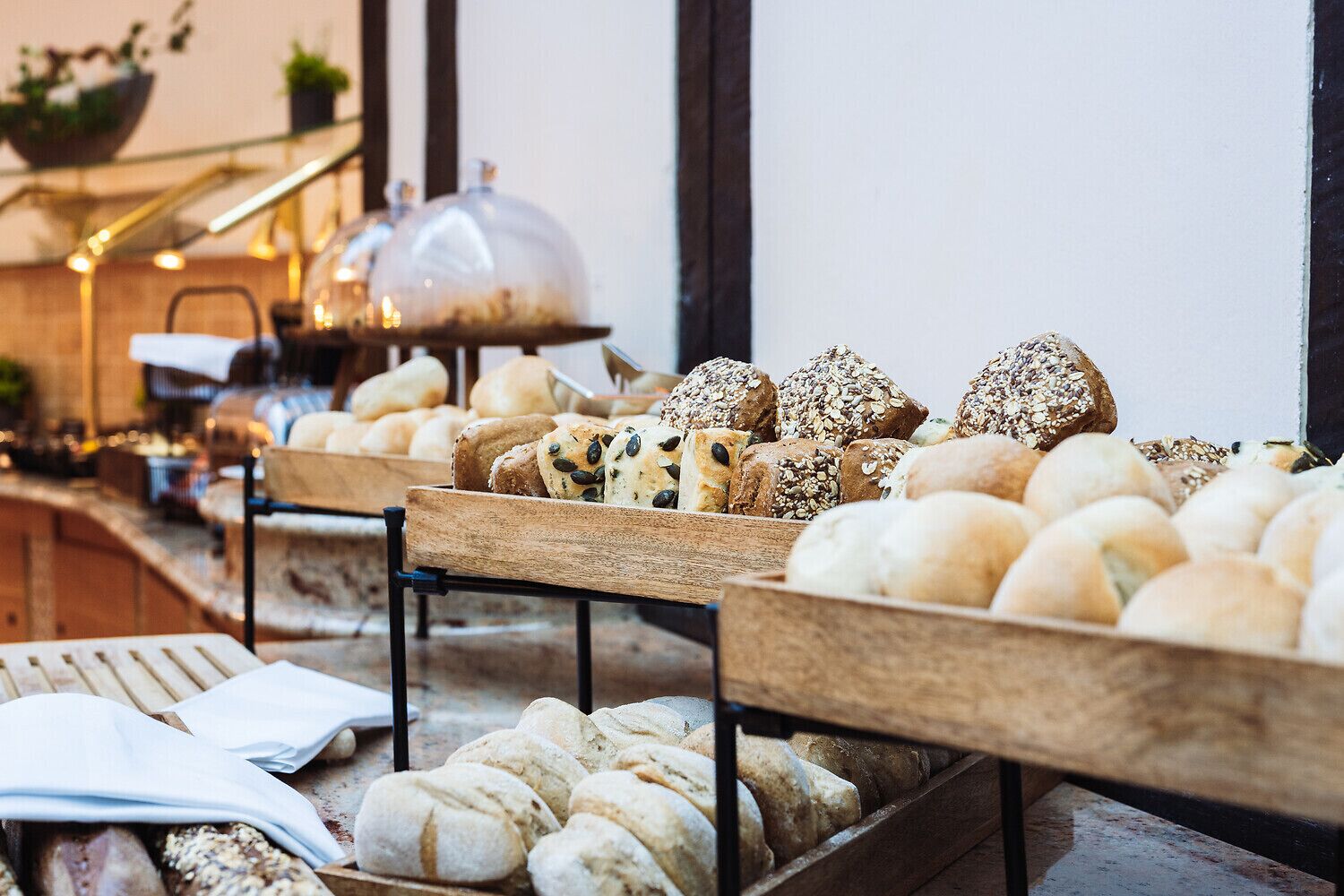 A variety of breads and pastries displayed on wooden stands in a bakery setting.