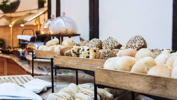 A variety of breads and pastries displayed on wooden stands in a bakery setting.