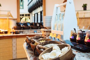 A buffet setup with various food items and condiments. - A-ROSA Gothisches Haus Wernigerode (Wernigerode)