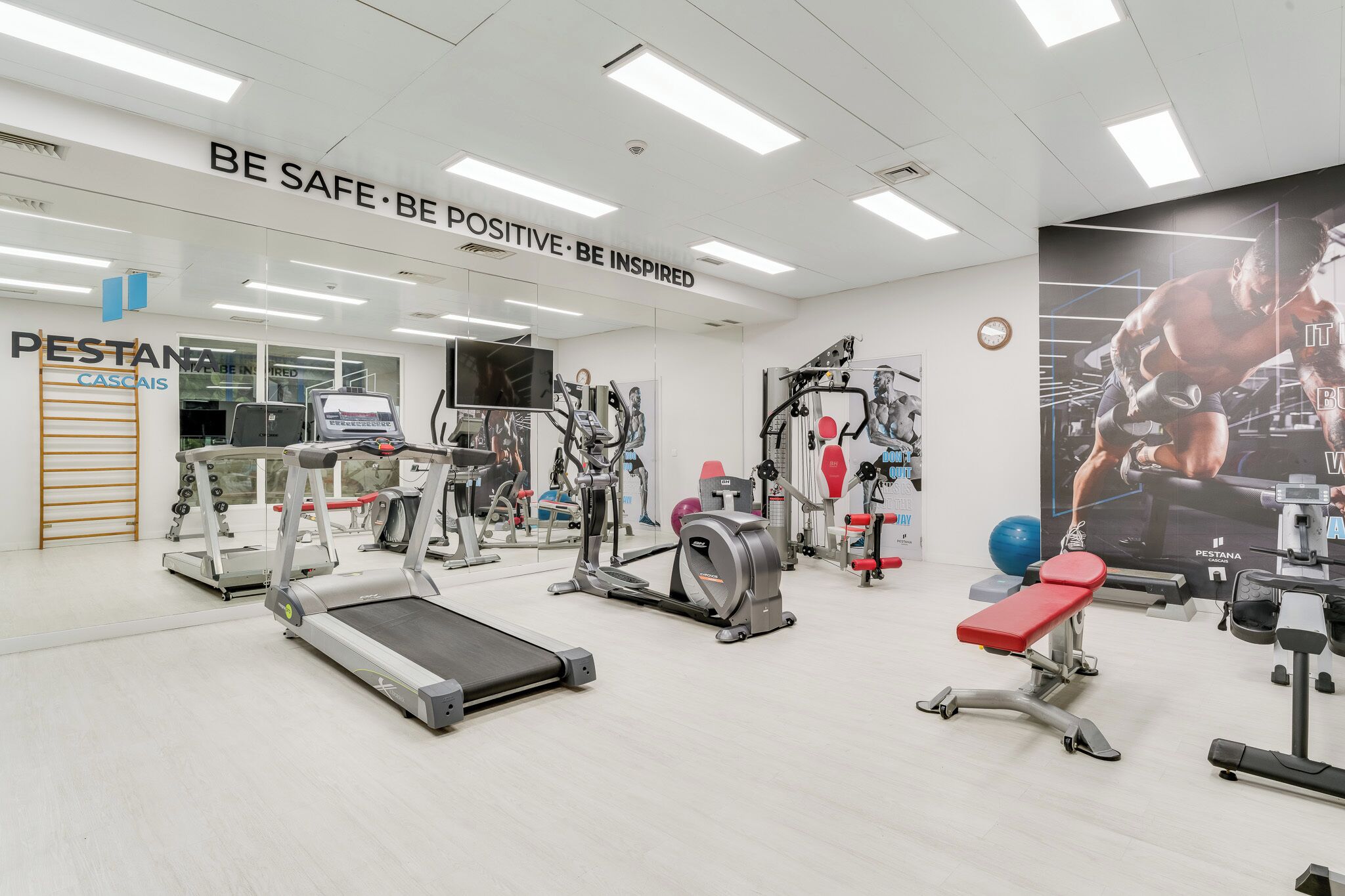 Ett gym med löpband, styrketräningsmaskiner och en motiverande affisch.