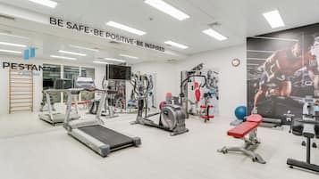 Un gimnasio con cintas de correr, máquinas de pesas y un cartel motivacional.