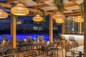 An outdoor dining area with wicker pendant lights, wooden tables, and chairs. - Pestana Cascais Ocean & Conference Aparthotel (Cascais)