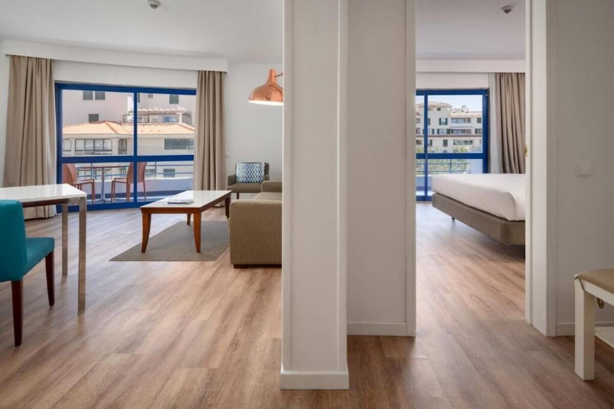 Une chambre d’hôtel avec un balcon, un coin repas et un lit.