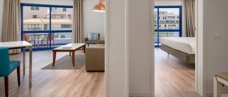 A hotel room with a balcony, a dining area, and a bed.