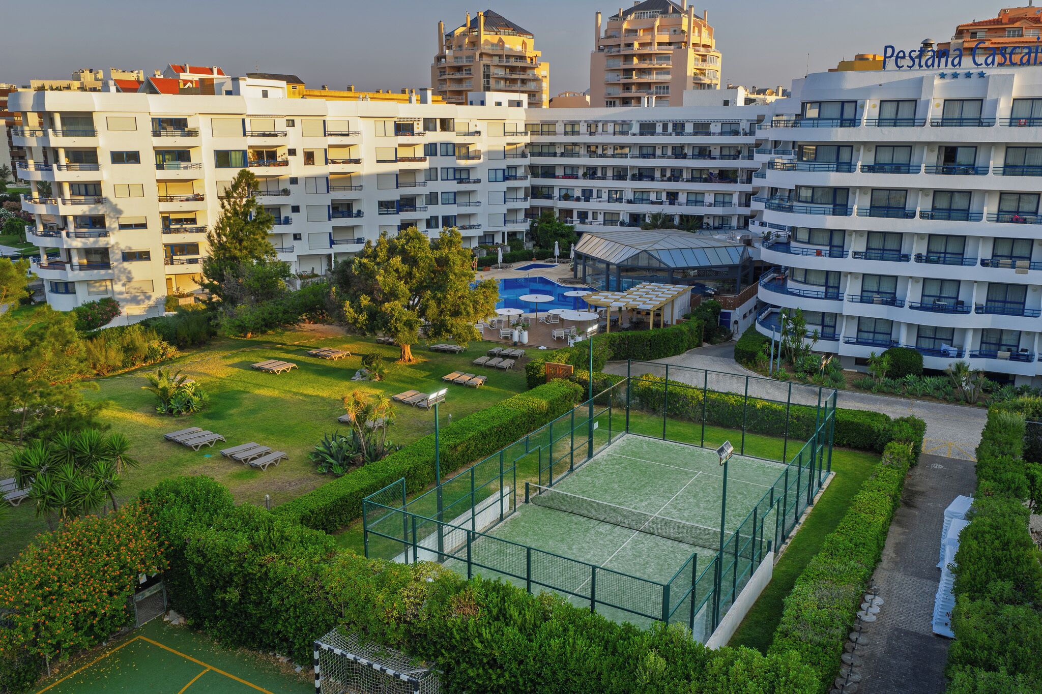 A multi-story hotel with a rooftop pool and tennis court.