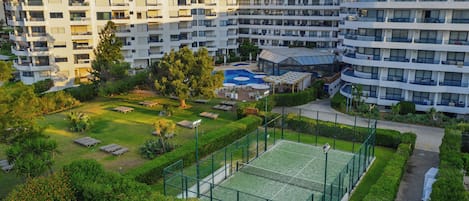 A multi-story hotel with a rooftop pool and tennis court.