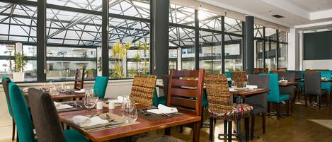 A restaurant with high ceilings, large windows, and modern furniture.