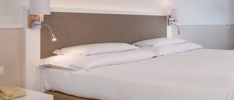 A hotel room with a large bed, a bedside table, a lamp, and a painting on the wall.