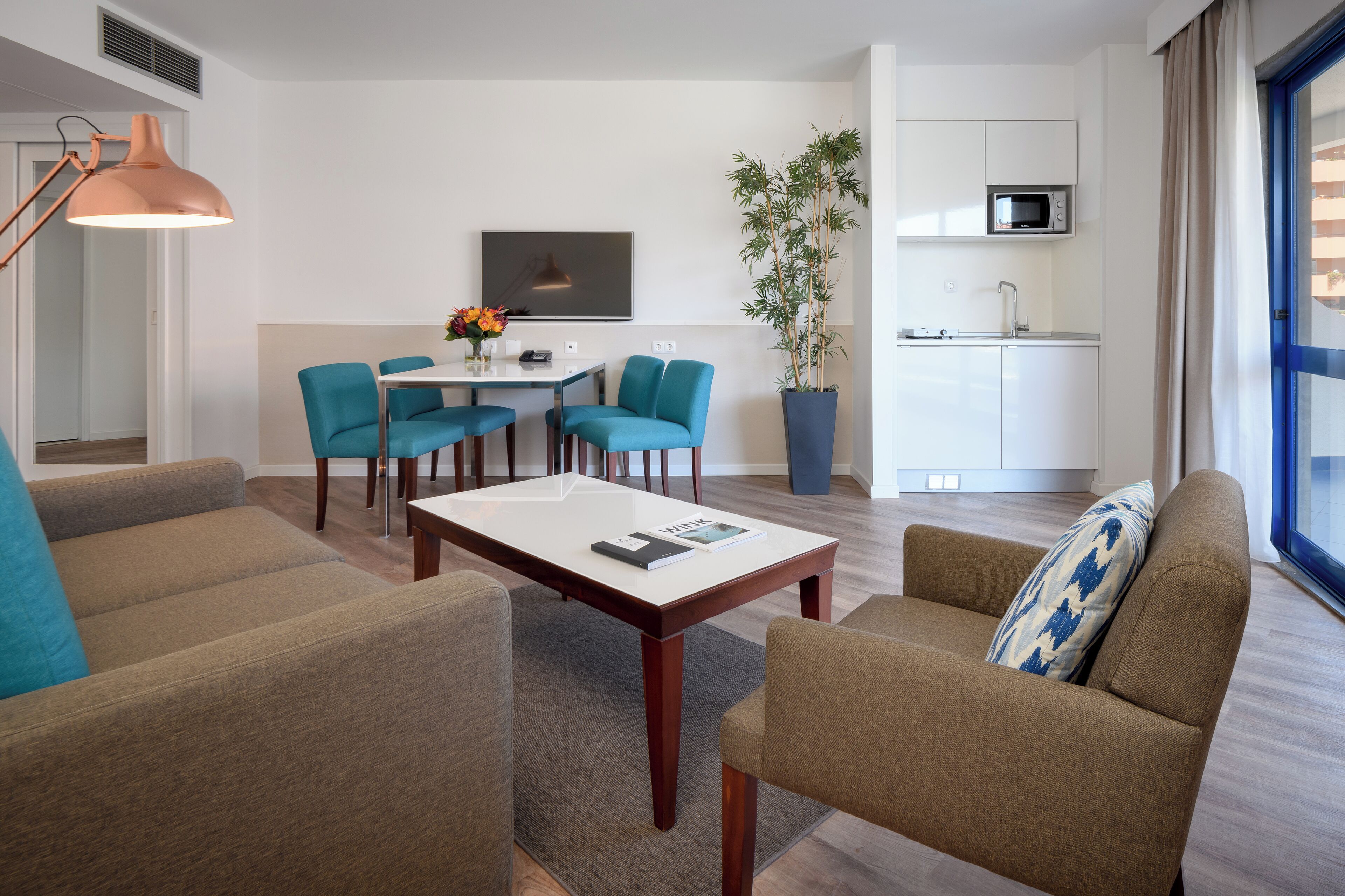 Una sala de estar moderna con comedor, cocina y un ventanal grande.
