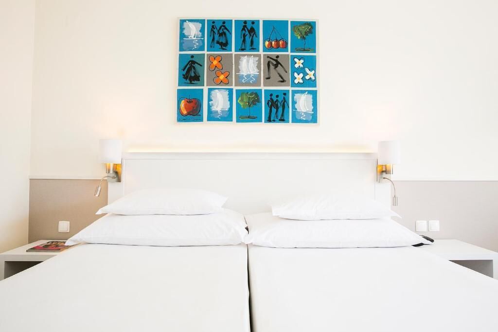 Una habitación de hotel con una cama, dos mesitas de noche y una obra de arte colgada en la pared.