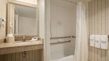 Une salle de bain équipée d’un lavabo, d’un miroir, d’un porte-serviettes et d’une douche.
