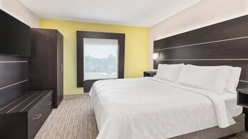 A hotel room with a bed, a nightstand, a wardrobe, and a window with a view of trees.