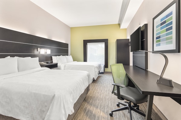 Habitación de hotel con dos camas, un escritorio, una silla, un televisor y una ventana.