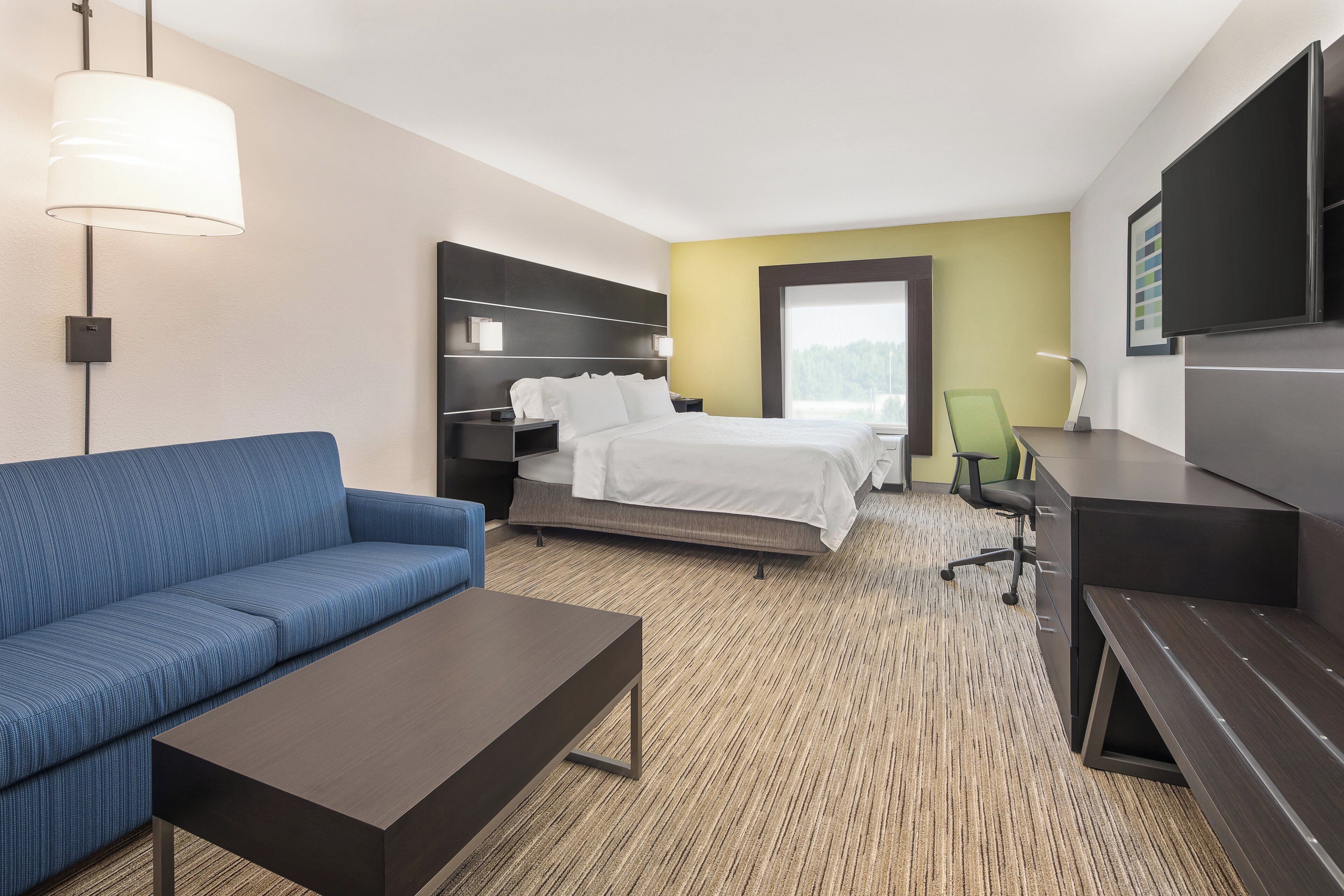 Habitación de hotel con cama, sofá, escritorio y televisión.