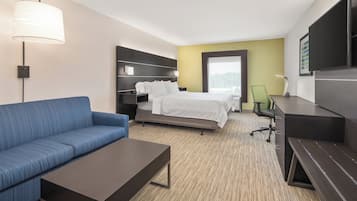 Habitación de hotel con cama, sofá, escritorio y televisión.