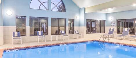 A swimming pool with lounge chairs and a sign indicating shallow water no diving allowed.