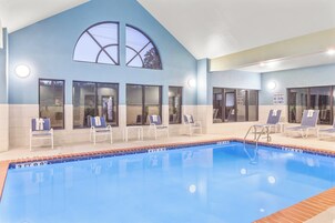 A swimming pool with lounge chairs and a sign indicating shallow water no diving allowed.