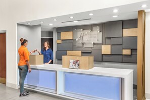 A hotel reception desk with a modern design, including a reception counter and a wall-mounted sign. - Holiday Inn Express & Suites Greenville-Spartanburg (Duncan) by IHG (Duncan)