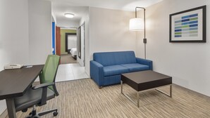 Une chambre d’hôtel équipée d’un bureau, d’un fauteuil de bureau, d’un canapé et d’une petite table.