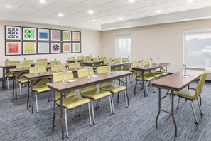 A conference room with multiple tables and chairs, framed artwork on the walls, and a large window with a view of a car. - Holiday Inn Express & Suites Greenville-Spartanburg (Duncan) by IHG (Duncan)