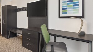 Une chambre d’hôtel moderne équipée d’un bureau, d’une chaise et d’un téléviseur à écran plat fixé au mur.