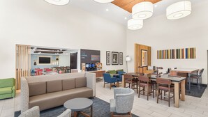 A modern hotel lobby with a sofa, chairs, a coffee bar, and a dining area. - Holiday Inn Express & Suites Greenville-Spartanburg (Duncan) by IHG (Duncan)